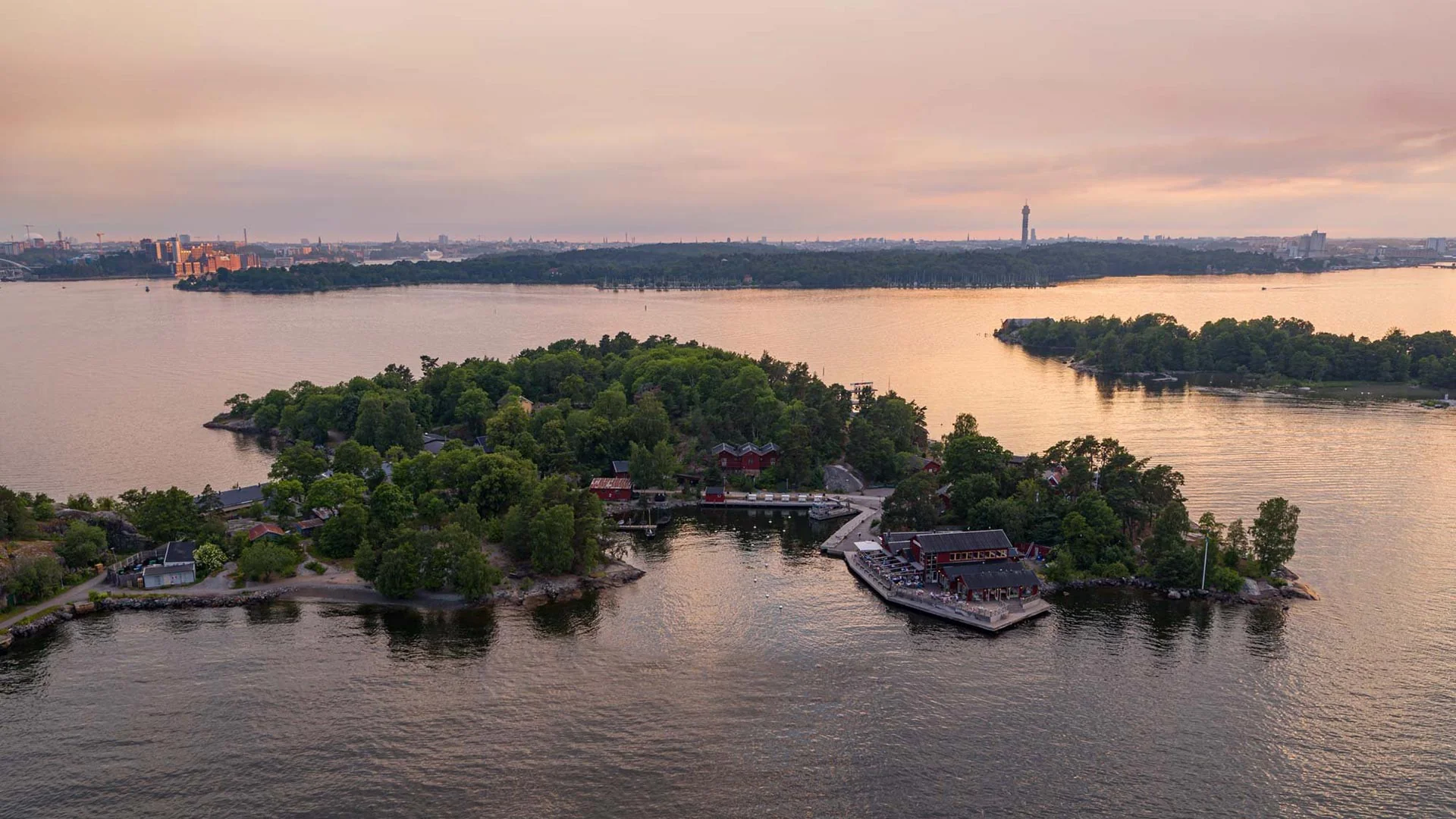 Aerial view of Fjäderholmarna at dusk, with the Stockholm skyline on the horizon