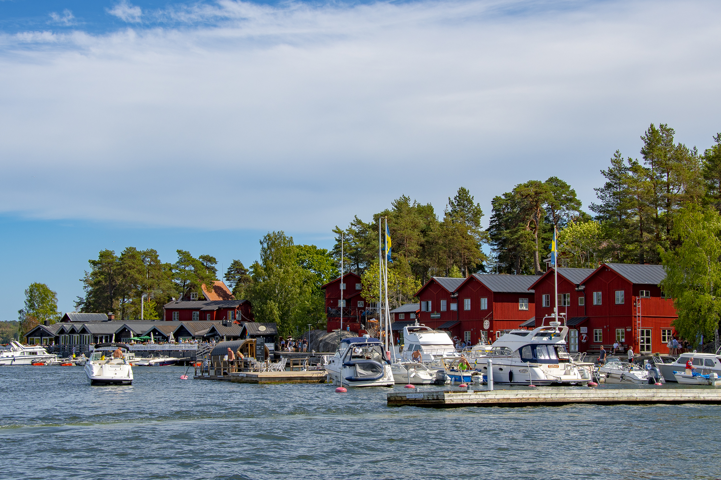 Red wooden buildings and motorboats in the harbour at Fjäderholmarna, Stockholm archipelago