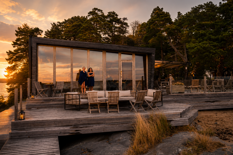 Guests on the deck of Sauna Panorama among pine trees at sunset