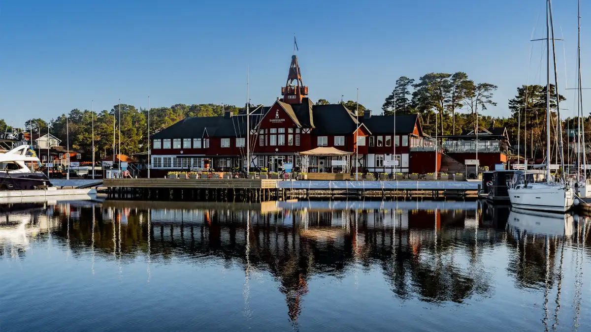 Red wooden building with a tower reflected in the calm harbour at Sandhamn