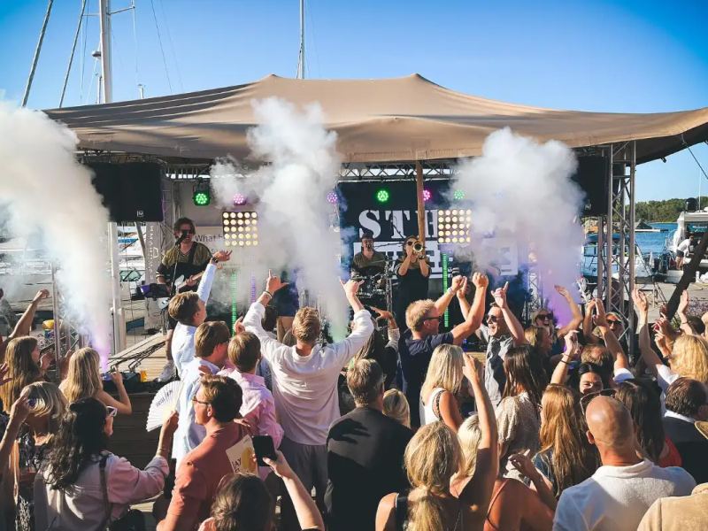 Crowd dancing at an outdoor stage party with smoke effects in Sandhamn