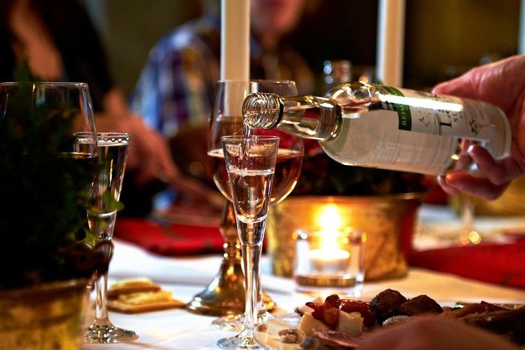 Glögg and snaps being poured by candlelight at a Christmas table in Stockholm