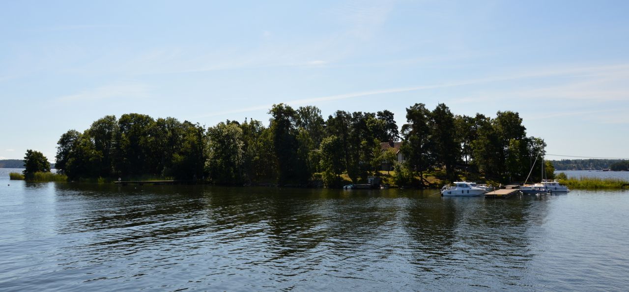 Getfoten island in the Stockholm archipelago seen from the water, with leafy trees and boats at its jetty
