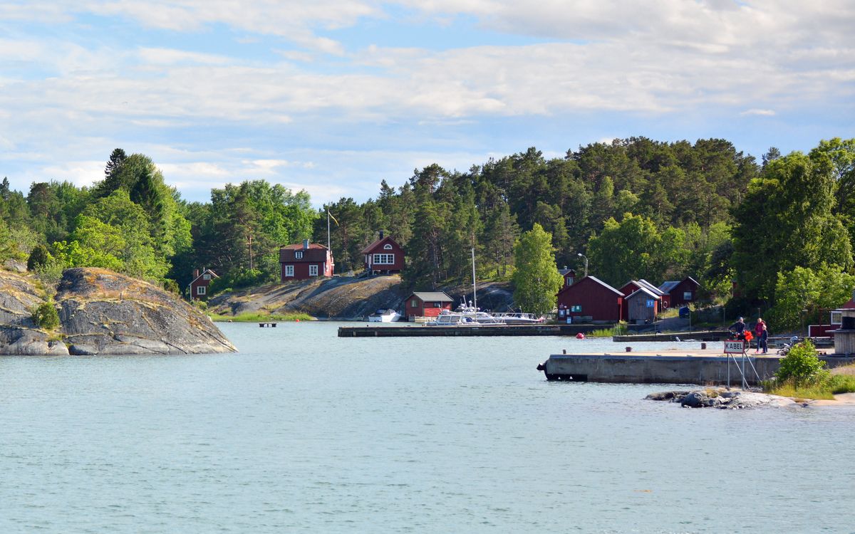 Red cottages, rocks and jetties along the shore of Möja, an island-hopping stop on a yacht charter in the Stockholm archipelago