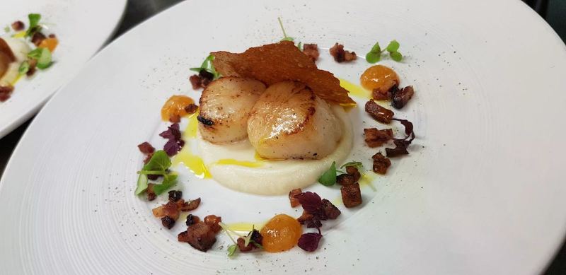 Seared scallops on a smooth purée with a crisp wafer, small crisp cubes, orange dots and micro herbs, plated at Sandhamns Värdshus in the Stockholm archipelago