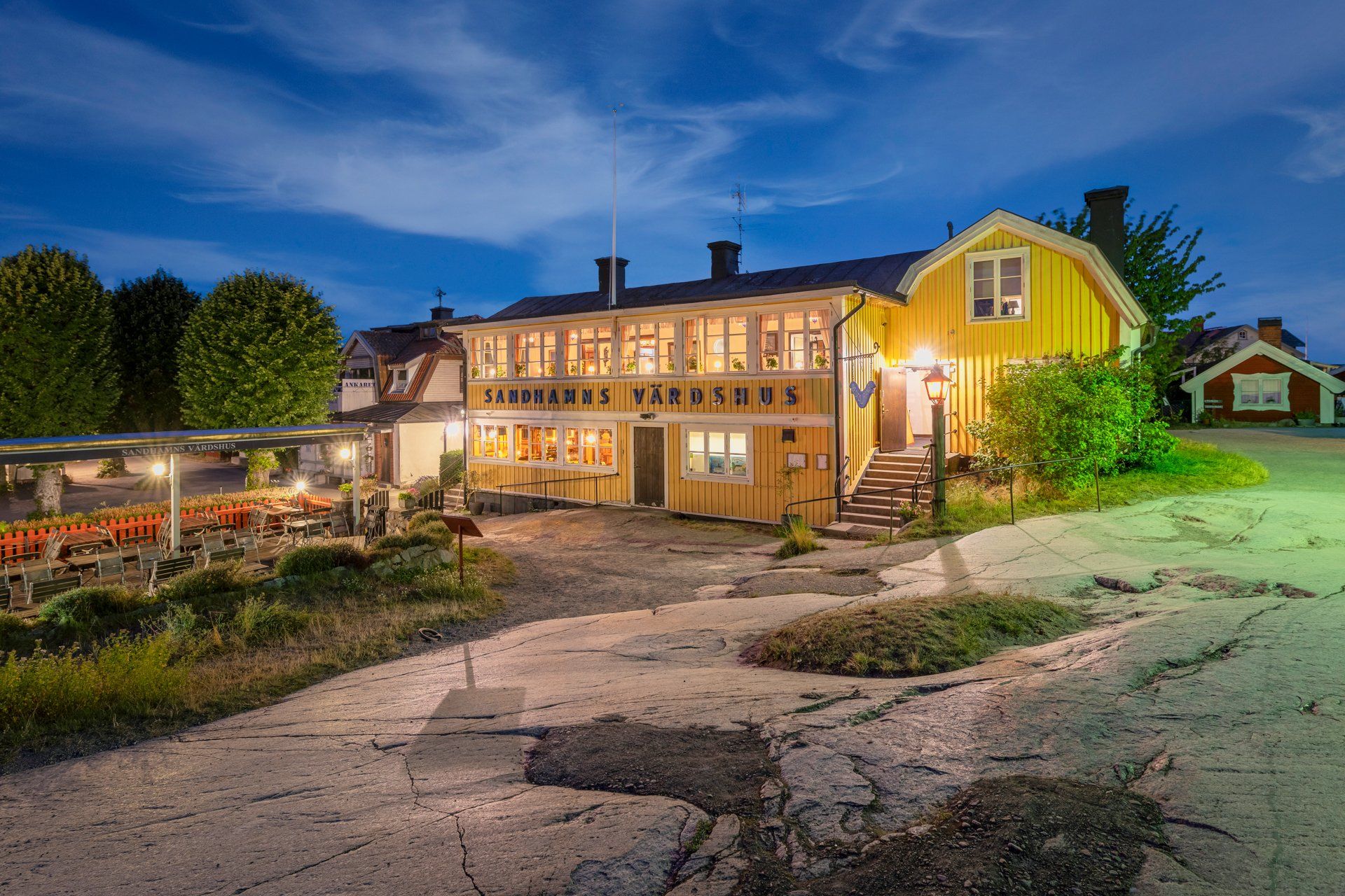 The yellow Sandhamns Värdshus building and its outdoor terrace at dusk on Sandhamn in the Stockholm archipelago