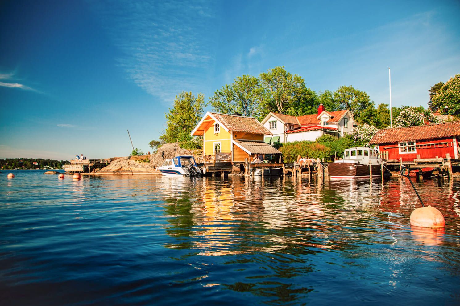 Yellow and red wooden houses by the water in Vaxholm at golden hour