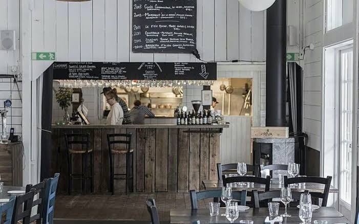 Rustic wooden bar with a chalkboard wine list and the open kitchen behind it at Svartsö Krog in the Stockholm archipelago