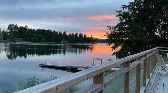 Wooden boardwalk and jetty by a calm bay at sunset on Ornö in the Stockholm archipelago