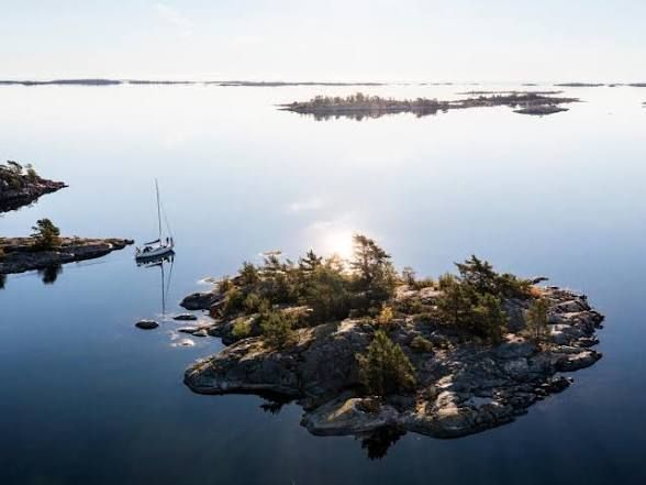 Rocky islet and an anchored sailing boat on calm water off Ornö in the Stockholm archipelago
