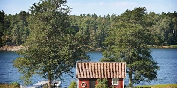 Small red cottage by the water among tall trees on Ornö in the Stockholm archipelago