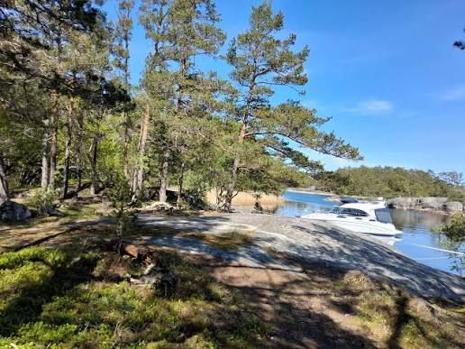 Motorboat moored by smooth rocks and pine trees on Ingmarsö in the Stockholm archipelago