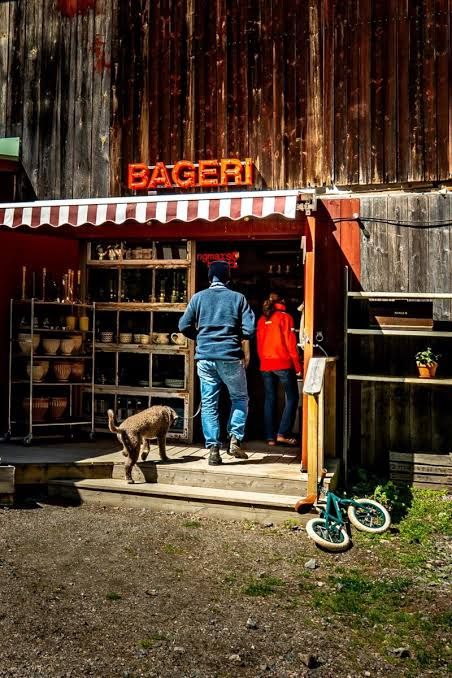 Visitors at a wooden bakery with an orange Bageri sign on Ingmarsö in the Stockholm archipelago