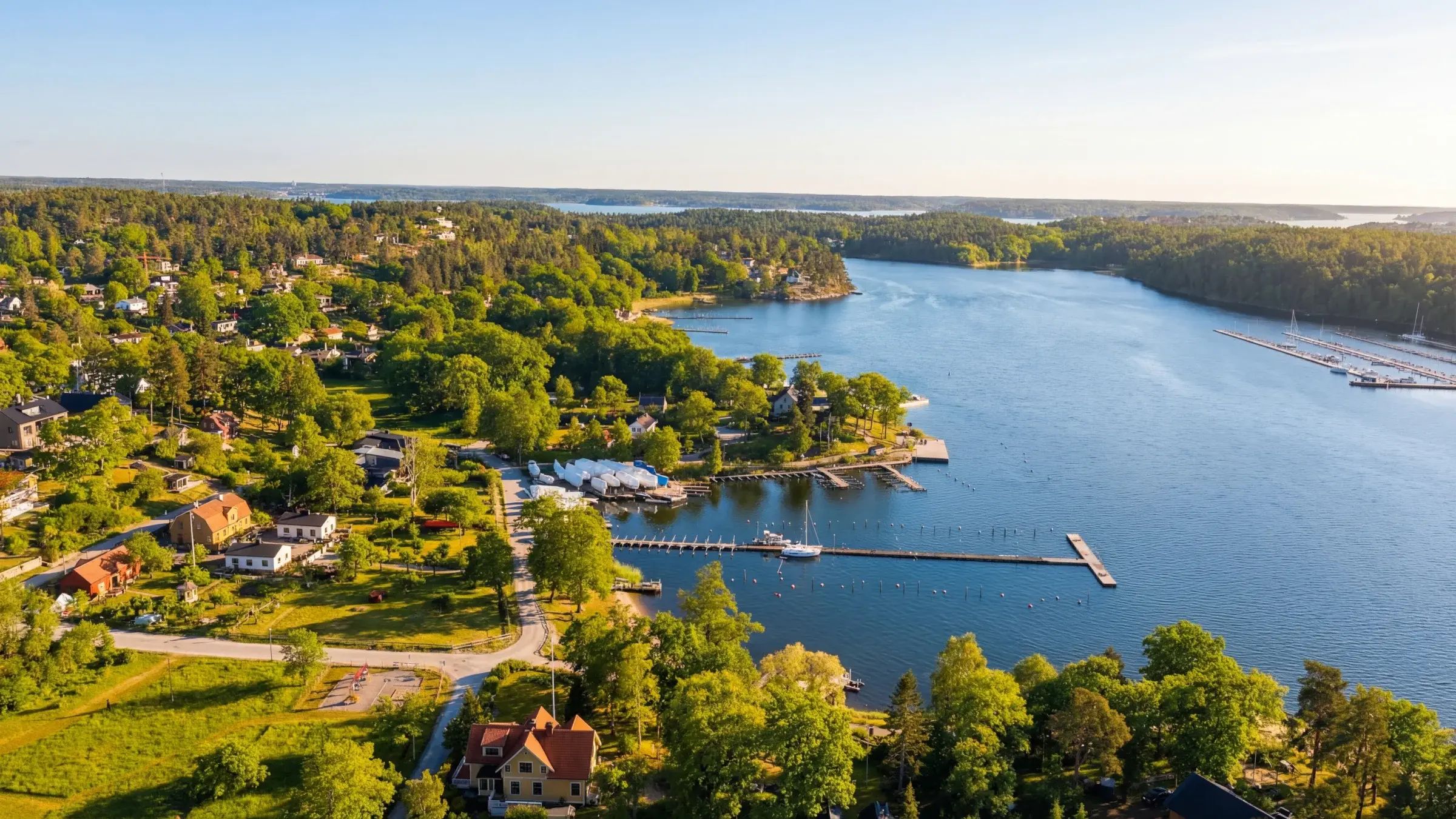 Aerial view of a wooded shoreline, bay and jetties around The Old Smokehouse