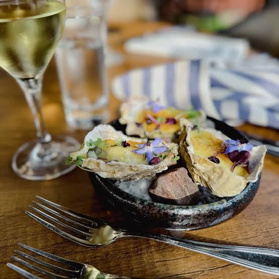 Oysters with edible flowers and a glass of white wine on a restaurant table on Utö