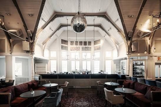 Bar and lounge with a mirror ball under a high, vaulted white wooden ceiling at Seglarhotellet on Sandhamn, Stockholm archipelago