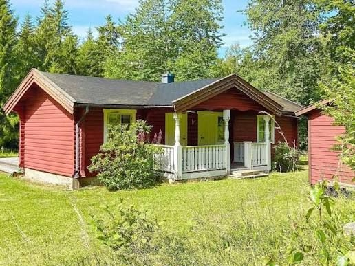 Red cottage with a white veranda surrounded by trees on Blidö, Stockholm archipelago