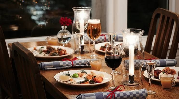 Candlelit dinner table with plated dishes, beer and red wine at Restaurang J in Nacka Strand, Stockholm