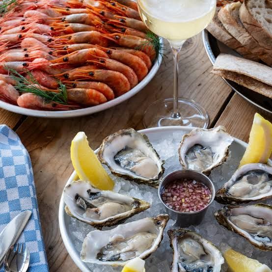Oysters on ice with lemon and shallots, a platter of prawns, bread and white wine at Restaurang J in Nacka Strand, Stockholm