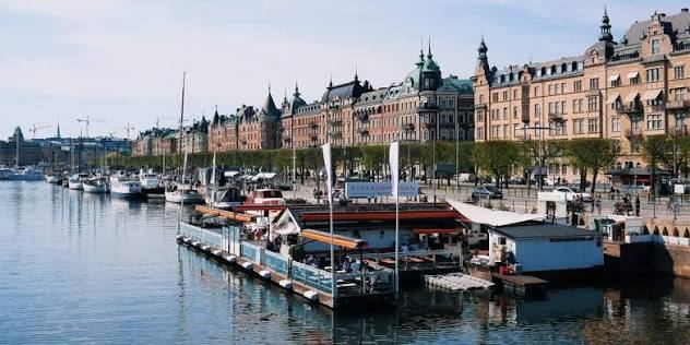 Strandbryggan's floating restaurant along the quay at Strandvägen in Stockholm, with moored boats and grand stone buildings, easy to reach by boat