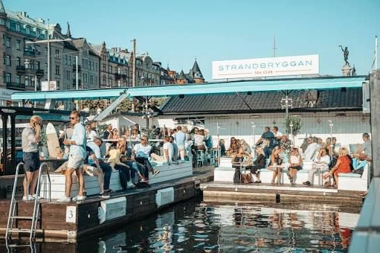 Strandbryggan Sea Club's sign above guests on the floating pontoons by Strandvägen in Stockholm