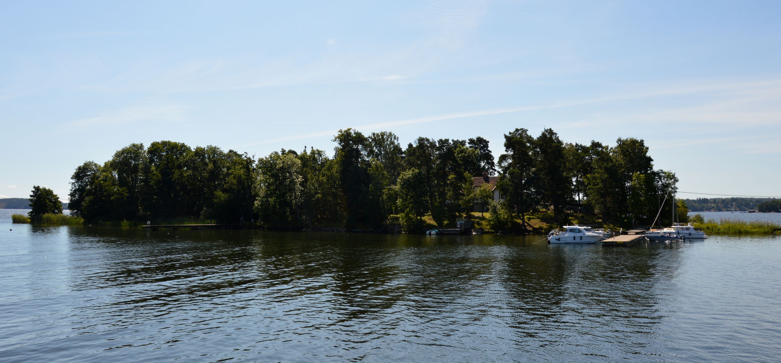 Getfoten's tree-lined shore and guest jetty on a calm summer day