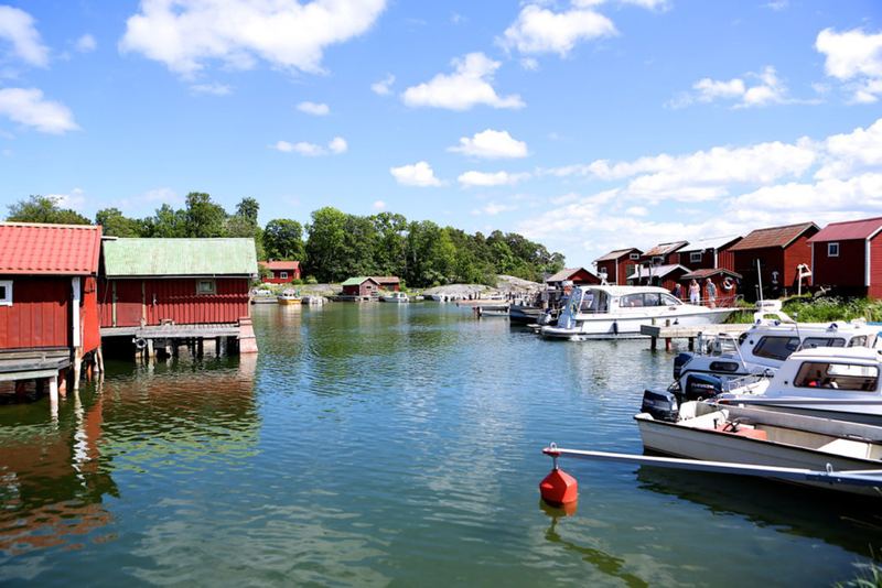 Red boathouses and motorboats in a calm harbour on Möja