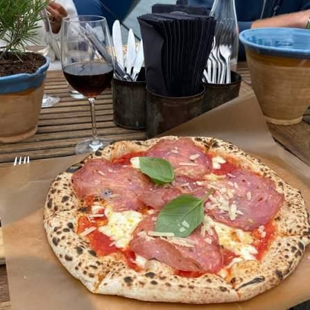 Pizza with cured ham and basil served with red wine at Harö in the Stockholm archipelago