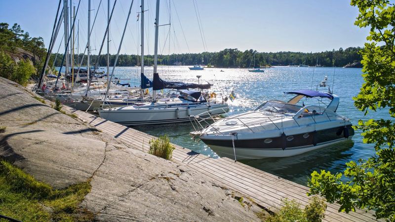 Boats moored alongside a wooden jetty and smooth granite rock at Finnhamn