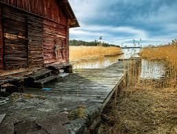 Old wooden boathouse and stone jetty by a reed-lined inlet on Nämdö in the Stockholm archipelago