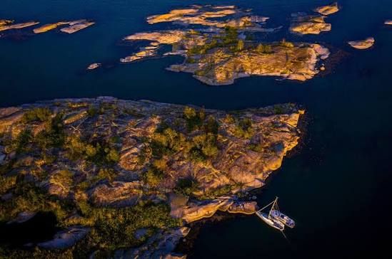 Aerial view of rocky islets and a moored sailing boat off Nämdö in the Stockholm archipelago