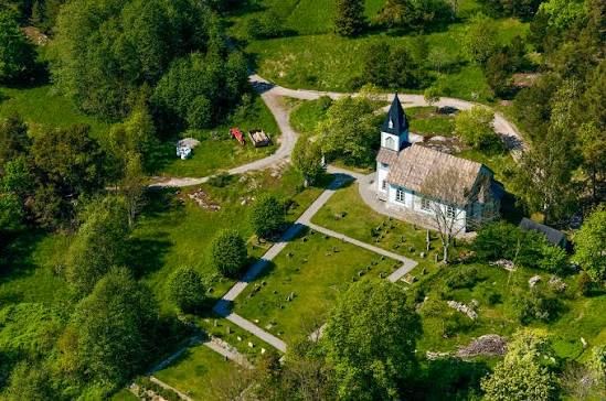Aerial view of a white church surrounded by meadows and trees on Nämdö, Stockholm archipelago