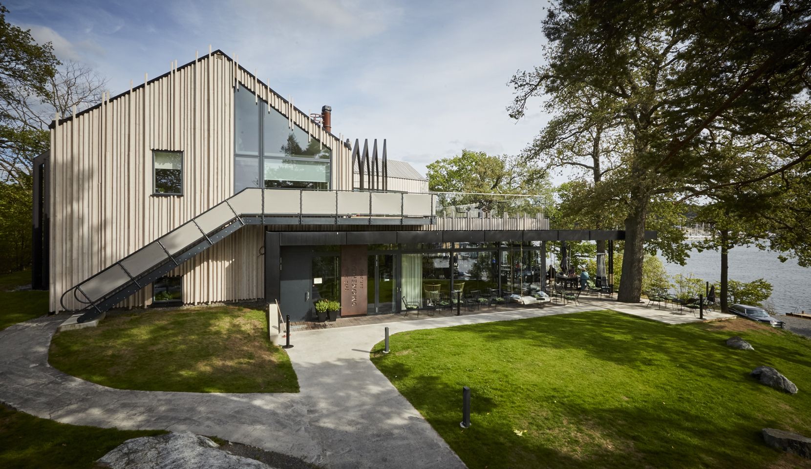 Modern timber-clad building with large windows and a lawn at The Old Smokehouse