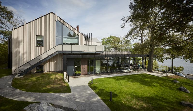 Modern timber-clad building with large windows and a lawn at The Old Smokehouse