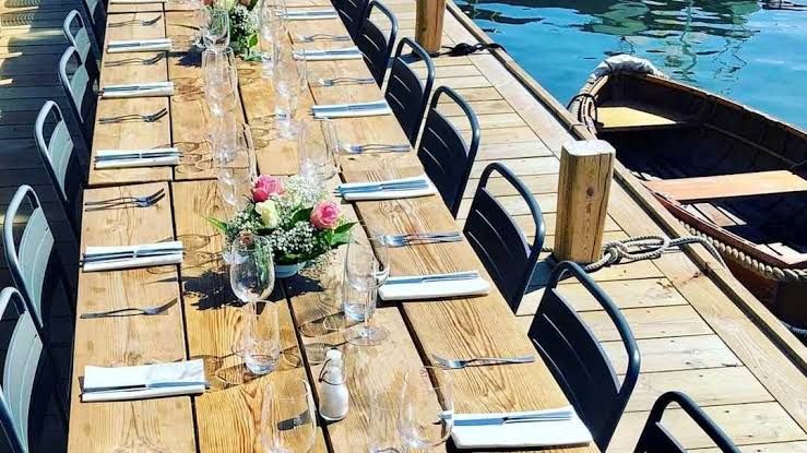 Long table set for a party on the jetty beside a moored wooden rowing boat at Motorverkstan Bistro & Bar, Stockholm archipelago