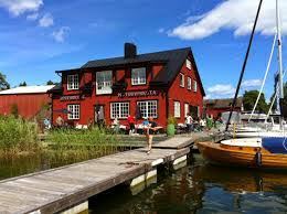 Red wooden restaurant building with a jetty and moored sailboats at Motorverkstan Bistro & Bar on Djurö, Stockholm archipelago