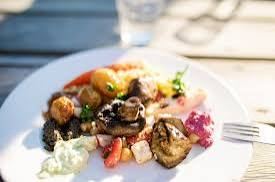 A plate of grilled vegetables, mushrooms and dips on a wooden table at Grundet in the Stockholm archipelago