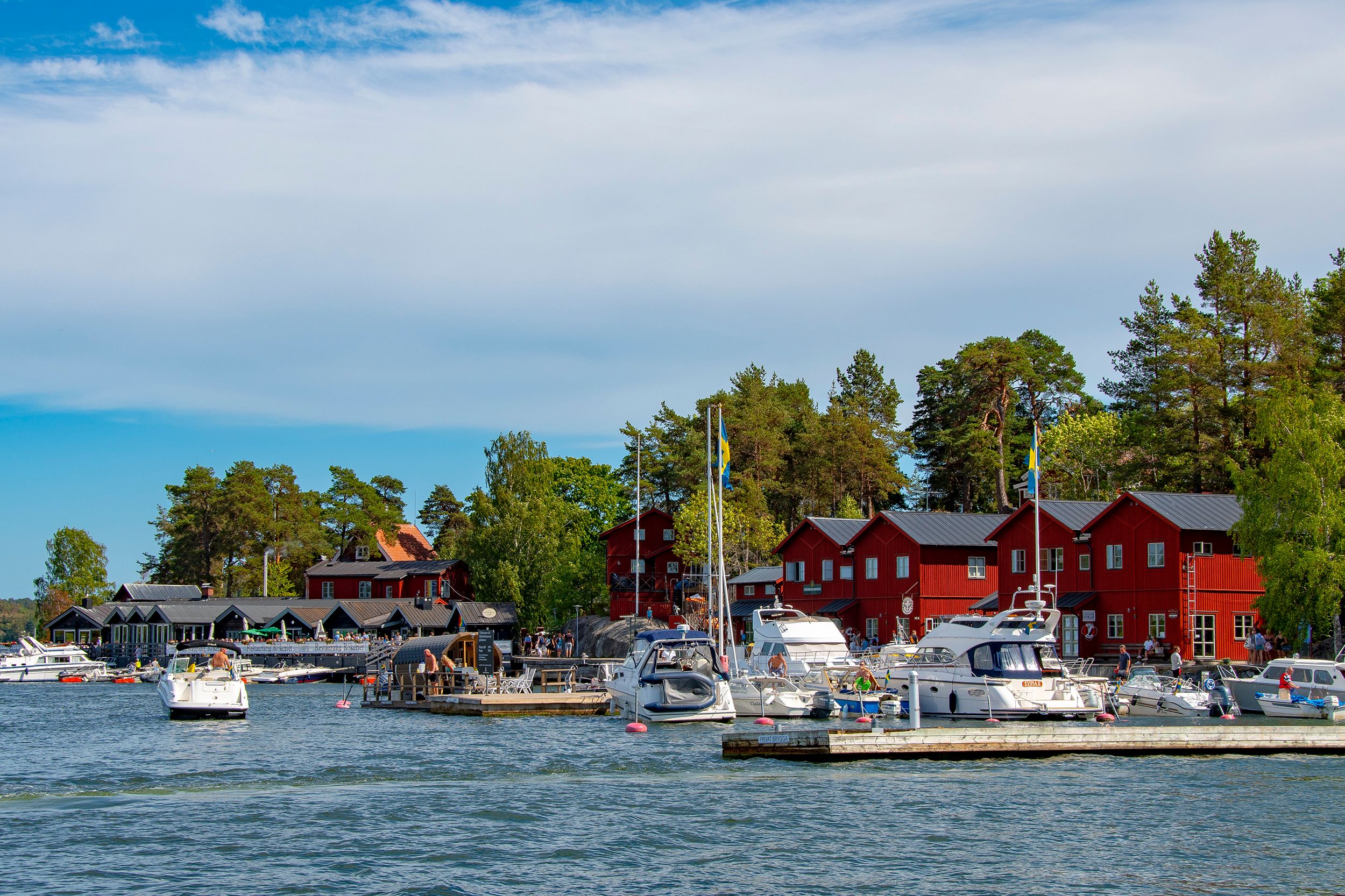 Red wooden buildings and motorboats in the harbour at Fjäderholmarna, Stockholm archipelago