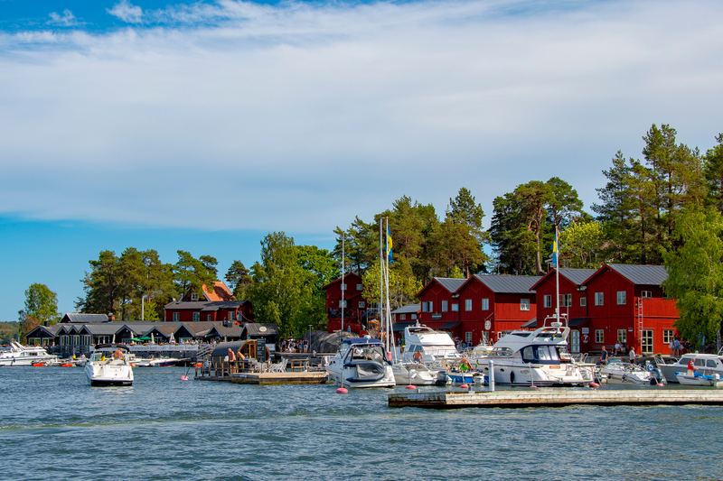 Red wooden buildings and motorboats in the harbour at Fjäderholmarna, Stockholm archipelago