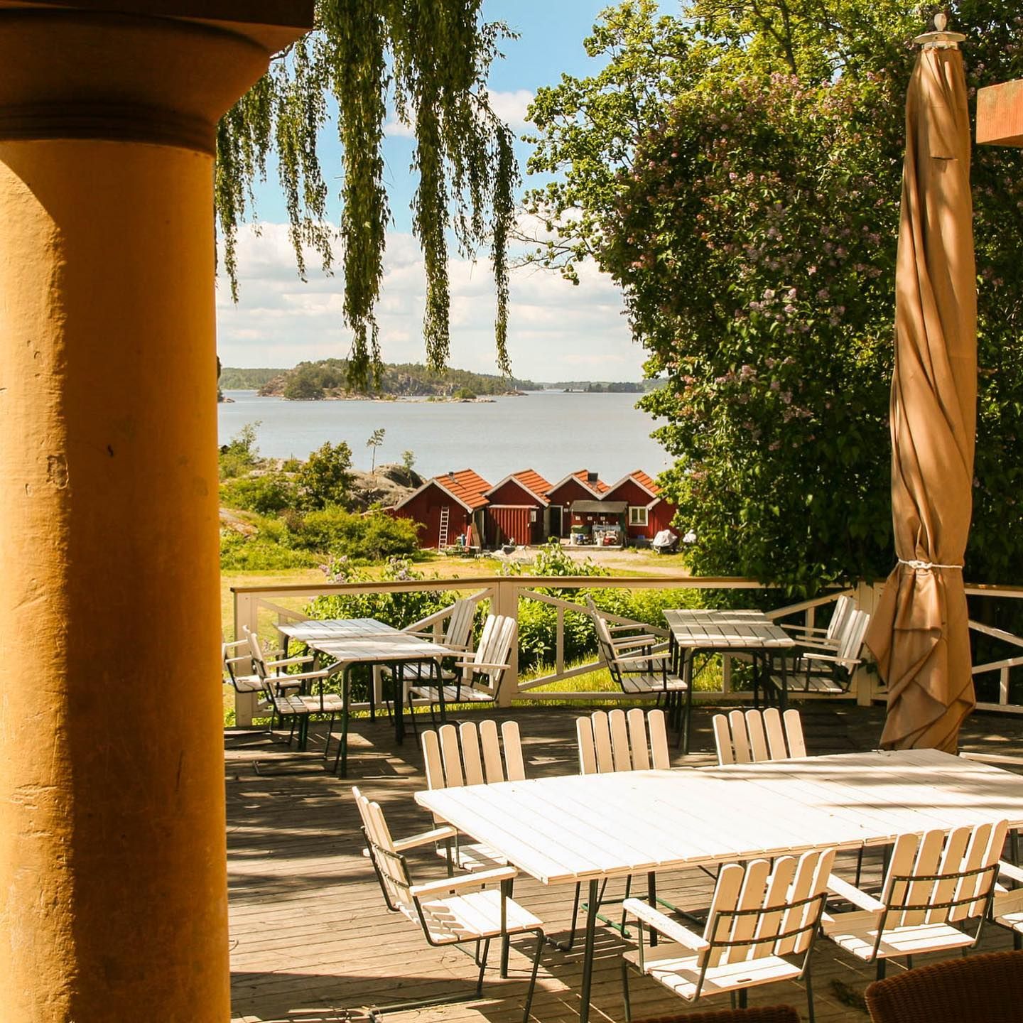 Outdoor terrace tables between yellow columns at Grinda Wärdshus, overlooking the bay