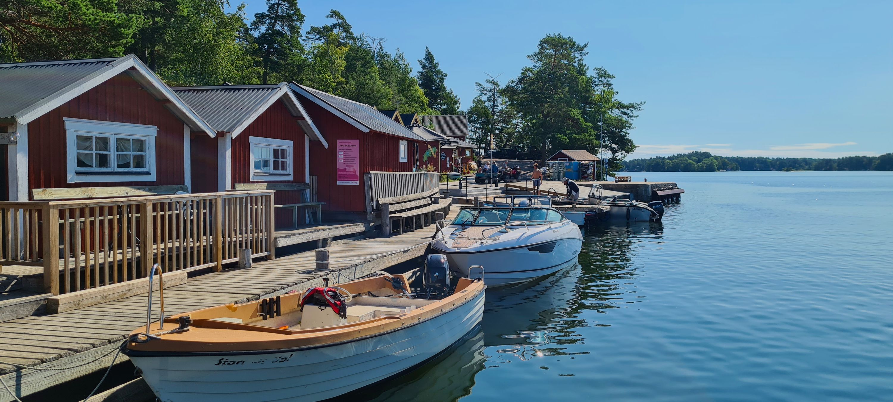 Red wooden houses and moored boats along a jetty on Svartsö