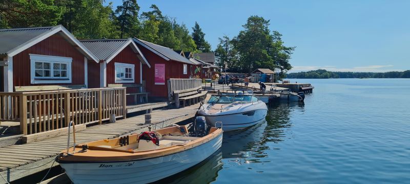 Red wooden houses and moored boats along a jetty on Svartsö
