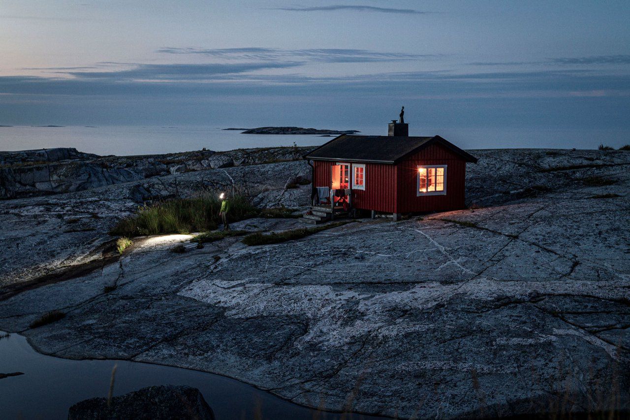Small red cabin on bare granite rock by the sea at dusk on Möja