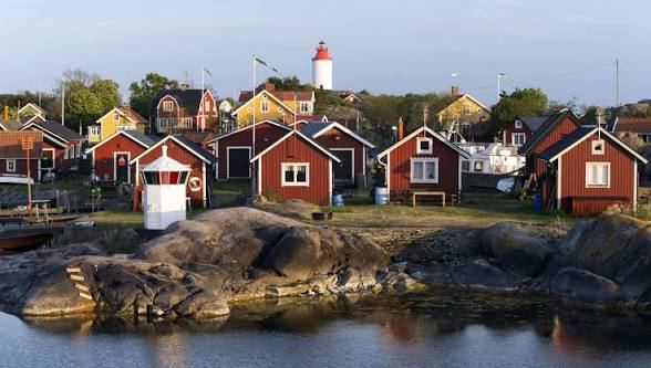 Red wooden houses on the rocks below Landsort lighthouse in the Stockholm archipelago
