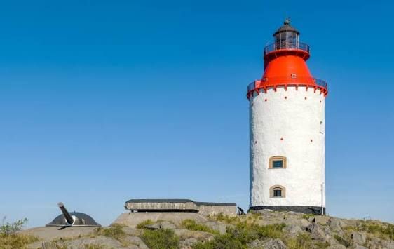 White Landsort lighthouse with a red top against a blue sky in the Stockholm archipelago