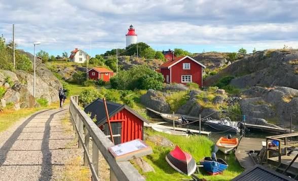Red wooden boathouses, small boats and Landsort lighthouse on Öja in the Stockholm archipelago