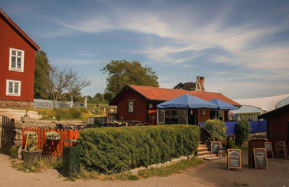 Red wooden buildings and an outdoor café with a blue parasol on Sandhamn