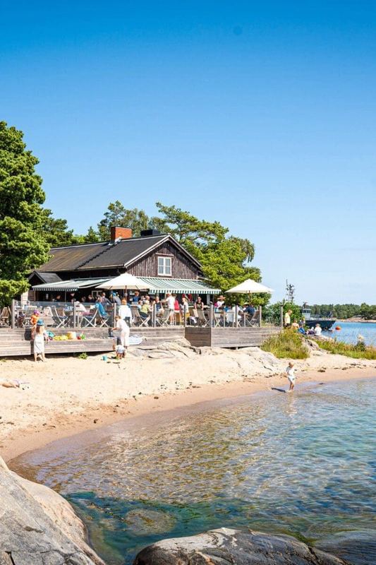 Sandy beach and waterside restaurant terrace with parasols on Idöborg