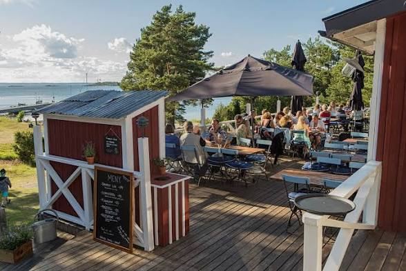 Guests on an outdoor restaurant terrace with parasols on Nåttarö in the Stockholm archipelago