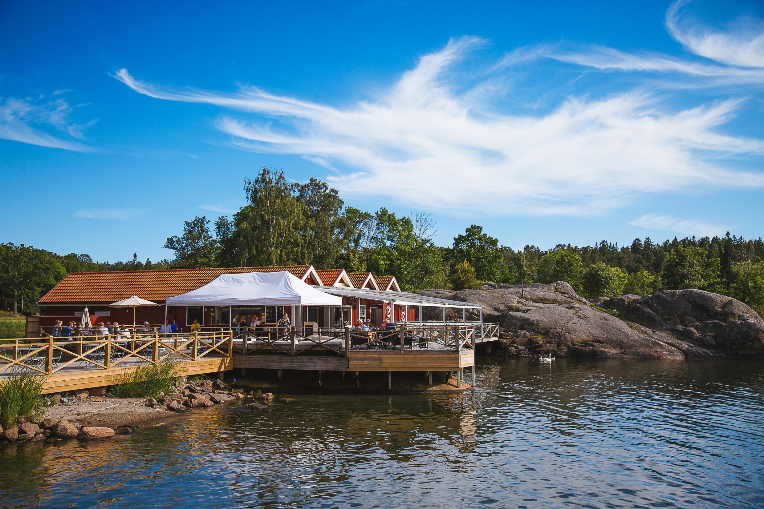 Waterside restaurant terrace with white tents by the rocks on Grinda